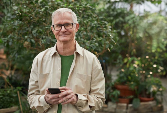 Middle aged man standing in his garden holding a mobile phone