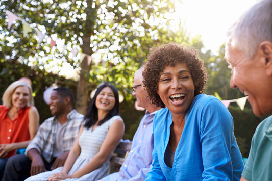 Group of people sitting outdoors, smiling and enjoying each other's company.